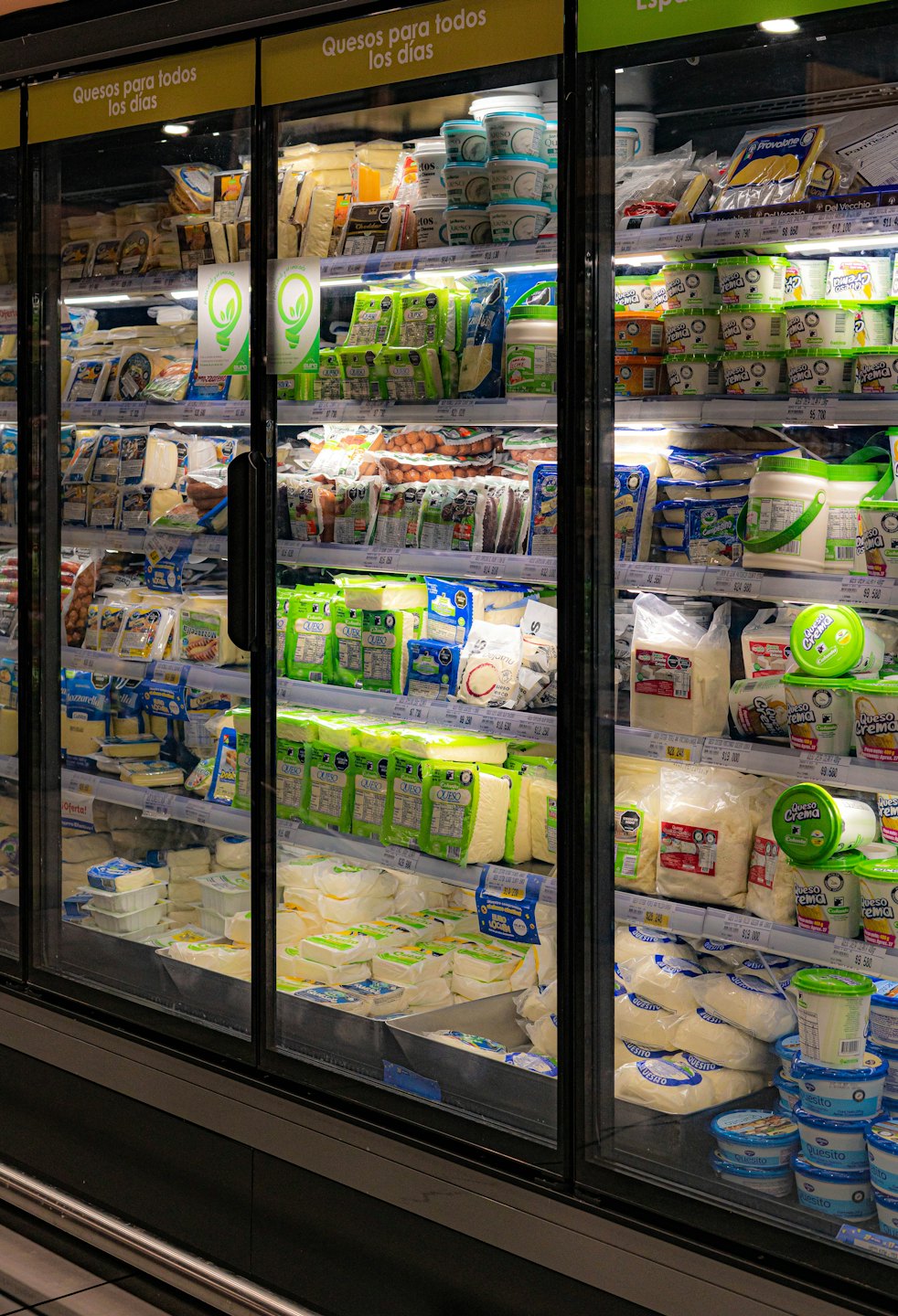 Productos lácteos ordenados en estantes dentro de una vitrina refrigerada de supermercado.