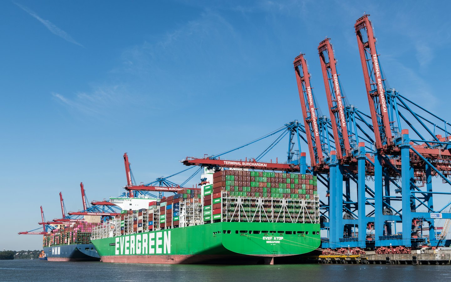Dos grandes buques portacontenedores atracados en un concurrido puerto de carga.