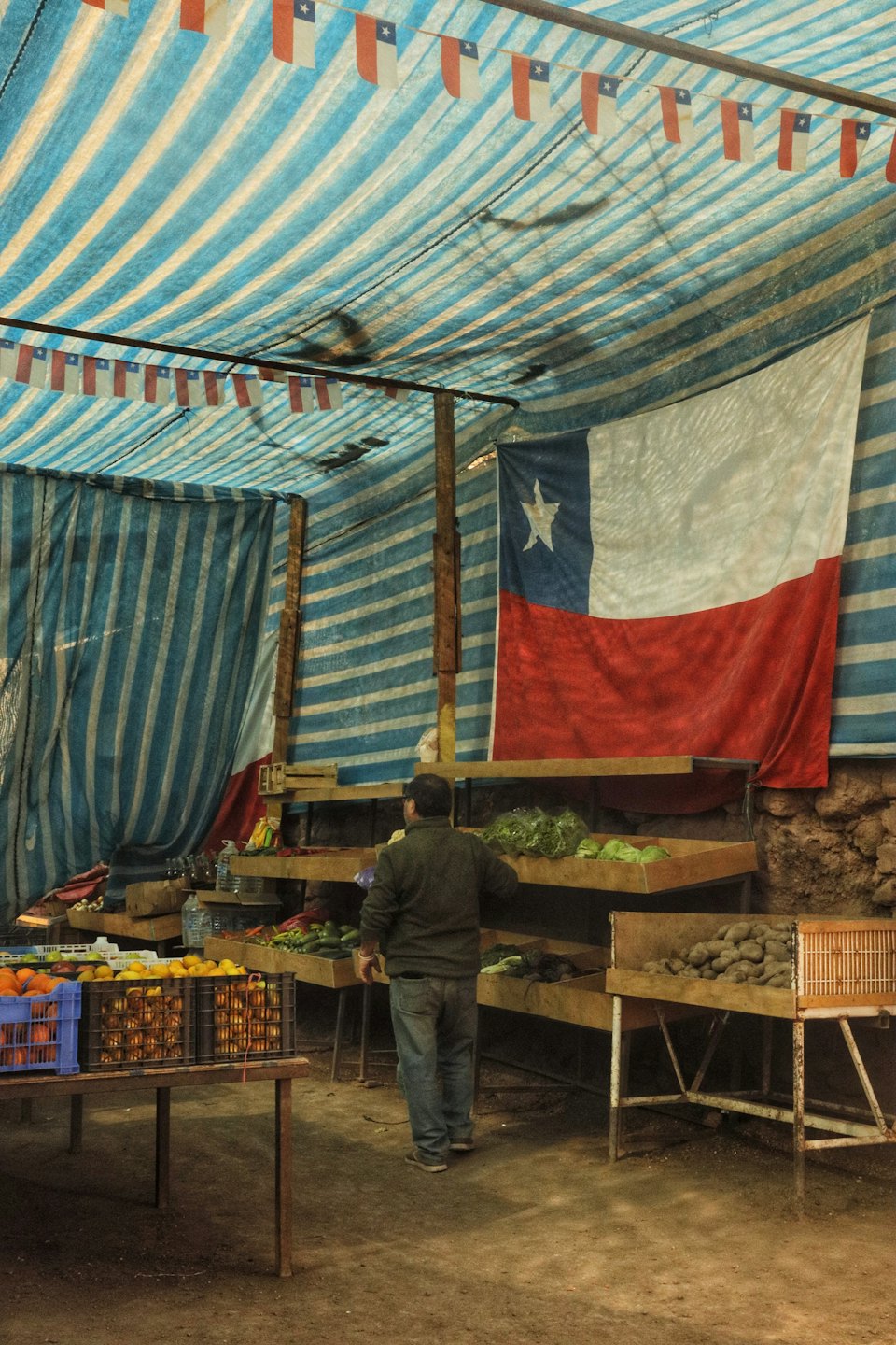 Un cliente examina productos frescos en un puesto de un mercado al aire libre.